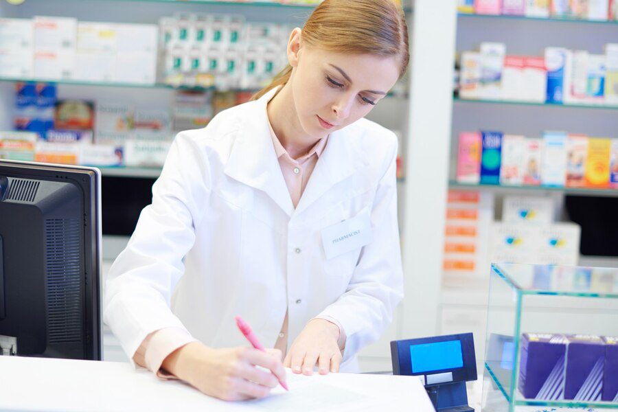 A woman in white lab coat writing on paper.