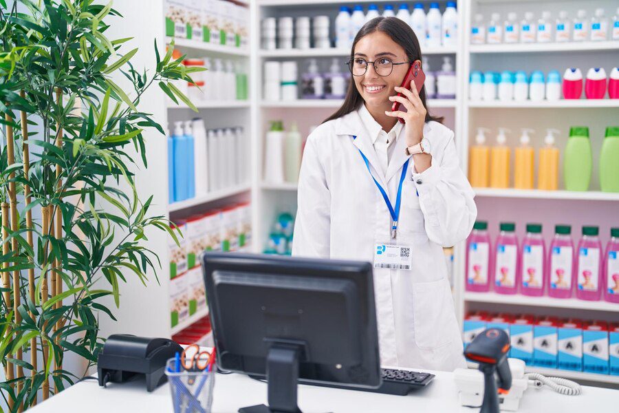 A pharmacist talking on the phone while standing in front of a computer.